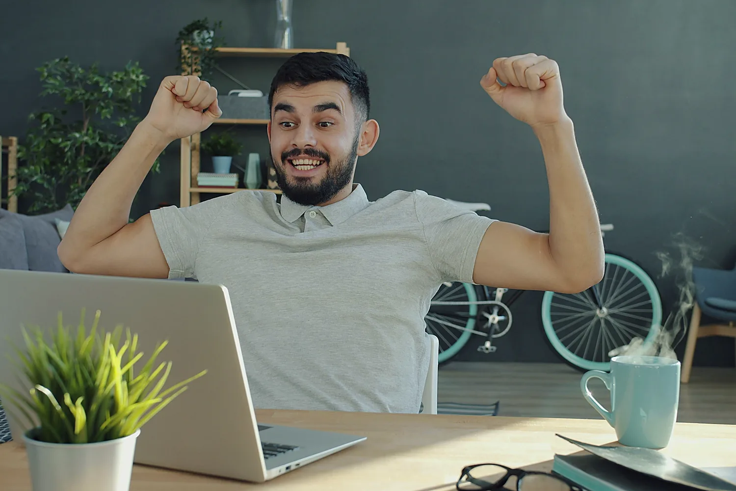A business owner celebrates a win at his laptop