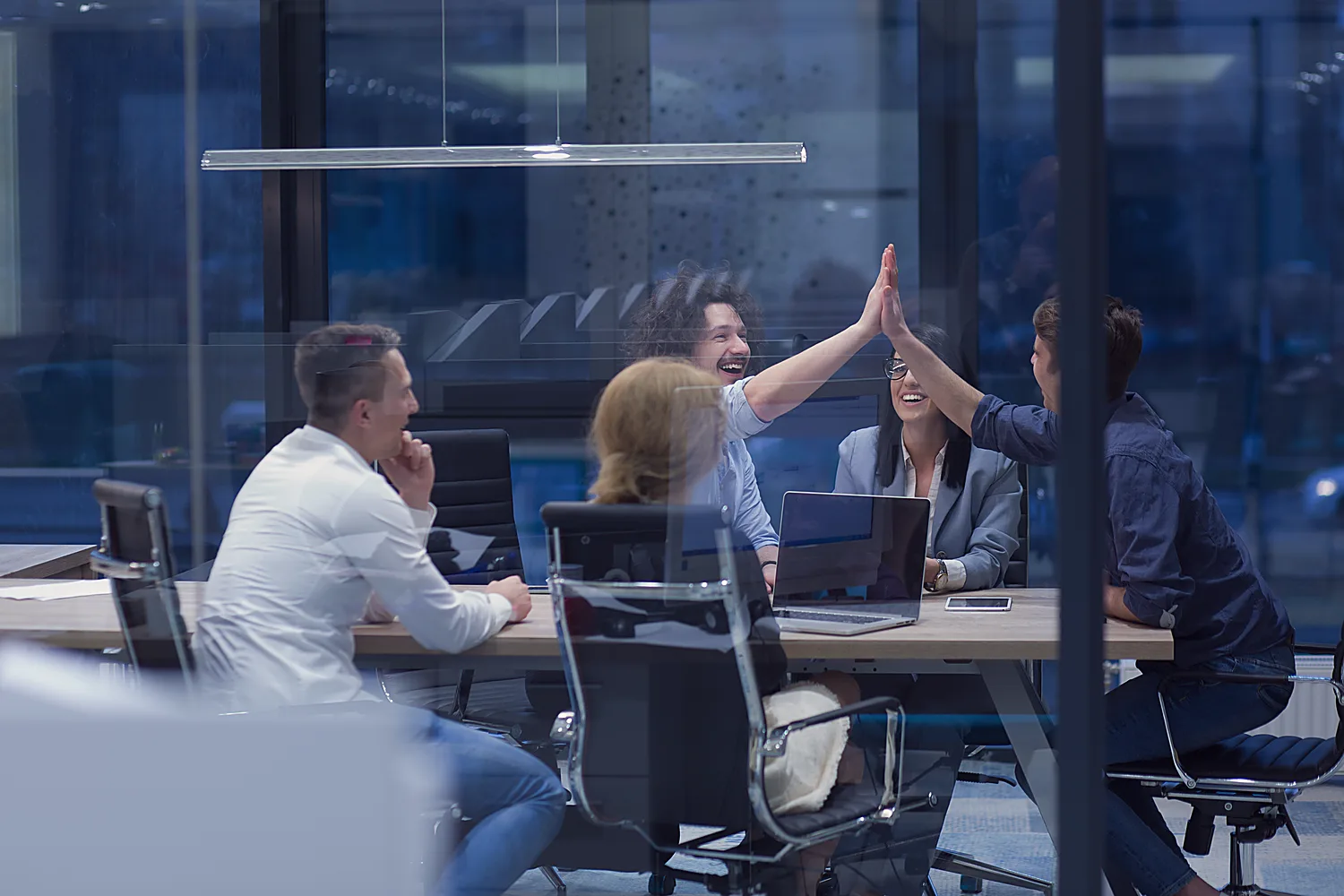 A team high-fives over a solved problem in an evening meeting